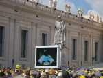 Ancient statue of St. Peter with the keys to heaven. Modern flat screen TV projecting the Pope for the crowd.